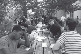 Writers Room participants in thought and writing at an outdoor workshop prior to community dinner. Photograph by Devin Welsh.