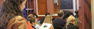 A student examines a RealArts informational brochure while listening to program speakers