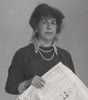A black and white photo of Nora Magid holding a newspaper
