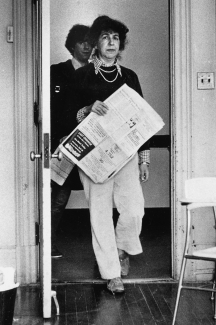 A black and white photograph of Nora Magid holding a newspaper