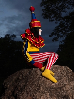 Photograph of a sad clown sitting on a rock at dusk